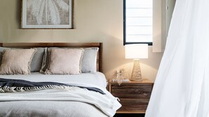 A neatly arranged bedroom with a bed, bedside table, lamp, and a framed artwork on the wall. - Villa Sangiovese - Unit One - 1-2 Heath Street (Evans Head)