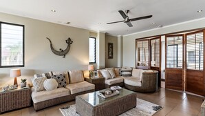 A spacious living room with a sofa set, a coffee table, and a decorative wall piece. - Villa Sangiovese - Unit One - 1-2 Heath Street (Evans Head)