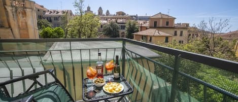 A balcony with a table set for a meal, overlooking a cityscape with historic buildings.