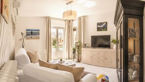 Un soggiorno moderno con un divano bianco, una TV a schermo piatto e un mobile contenitore con vetrate.