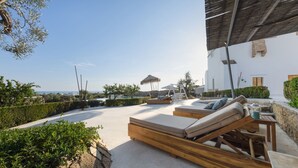 A sunlit outdoor lounge area with wooden loungers and a view of the sea. - Masseria Samenti - Suite Turchese with sea view (Torre Suda)