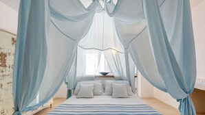 A bedroom with a bed under a blue canopy, white pillows, and a striped bedspread. - Masseria Samenti - Suite Turchese with sea view (Torre Suda)