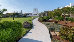A pathway leading to a white building with a tower, surrounded by well-maintained greenery and a clear sky. - Masseria Samenti - Suite Turchese with sea view (Torre Suda)