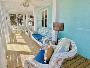 A covered porch with wicker furniture, a lamp, and a view of the outdoors.