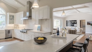 Una cocina moderna con armarios blancos, una isla grande e iluminación colgante.
