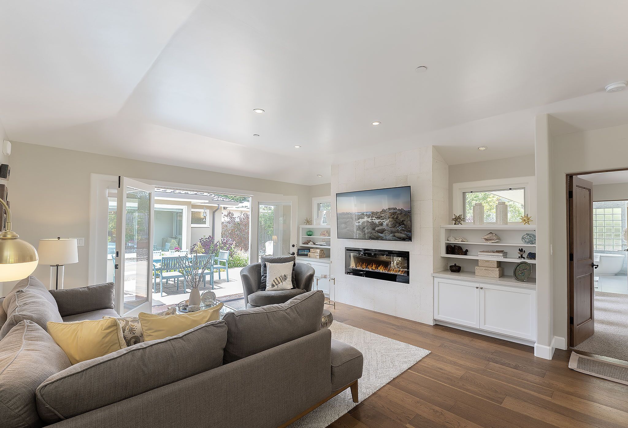 A modern living room with a grey sofa, a fireplace, and a TV mounted on the wall.