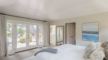 Un dormitorio con una cama grande, vistas a un patio exterior a través de puertas de cristal y un cuadro en la pared.