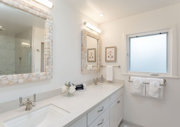 Une salle de bain avec deux lavabos, un grand miroir et une fenêtre.