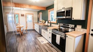 A modern kitchen with wooden cabinets, a stainless steel stove, and a microwave. - A pet-friendly, creek side ranch house w/starlink (Port Angeles)