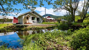 A small house with a porch, a pond in front, and a mountain in the background. - A pet-friendly, creek side ranch house w/starlink (Port Angeles)