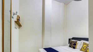 Un dormitorio con cama, mesita de noche y espejo.