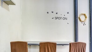 Una habitación con tres sillas marrones orientadas hacia una pizarra con la frase 'SPOT ON' y siluetas de pájaros.