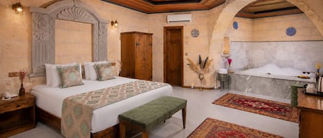 Un dormitorio con una cama grande, un banco, una bañera y una mesita.