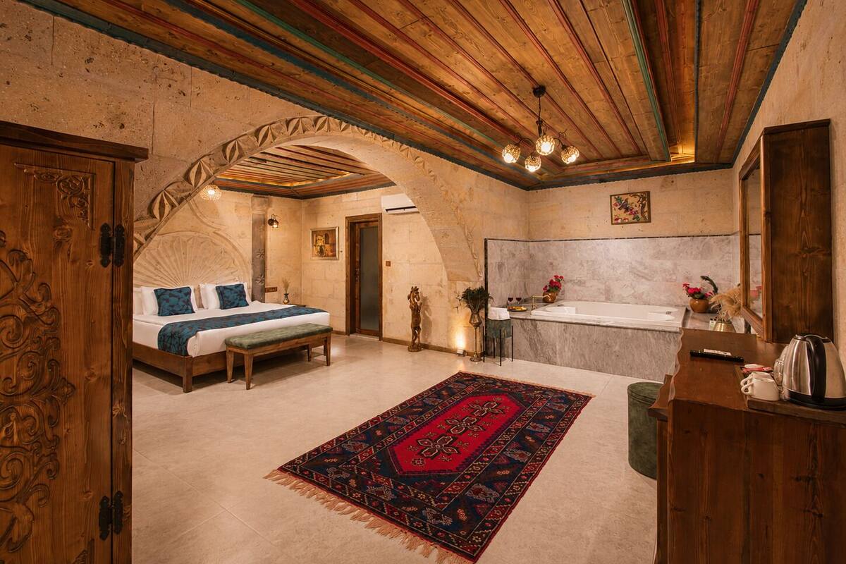 A room with a bed, a bathroom, and a wooden ceiling.