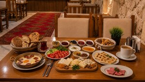 A dining table with various dishes, a coffee cup, and a buffet in the background. - Premium Cappadocia Hotel (Nevsehir)