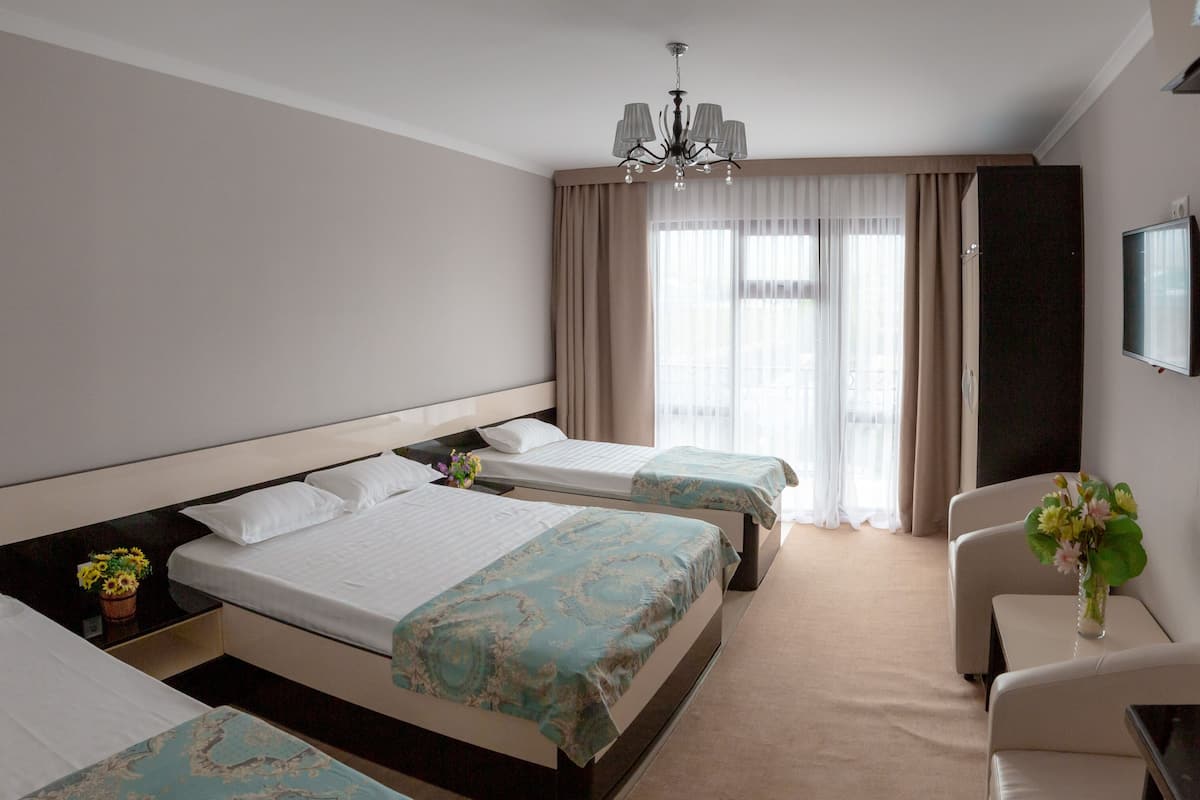 A hotel room with two beds, a desk, a chair, a television, and a window with curtains.