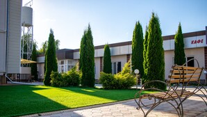 A courtyard with a paved walkway, a bench, and neatly trimmed hedges. - ololoFamily (Cholpon-Ata)