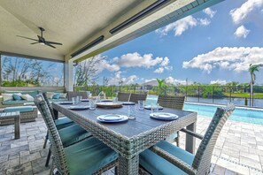 An outdoor dining area with wicker furniture and a view of a swimming pool.