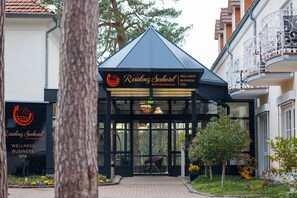 The entrance to a wellness business spa with a modern design, featuring a glass door and a small garden area with potted plants. - Residenz Seehotel Berlin Brandenburg (Mittenwalde)