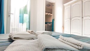 Ein Hotelzimmer mit Bett, Kleiderschrank und einem durchgegangenen Tür sichtbar liegendem Badezimmer.