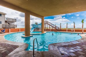 Relax by the pool, where a water slide awaits and steps lead to the fun.