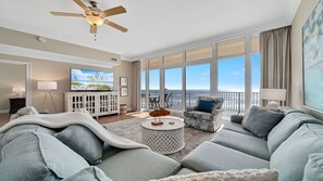 Relax in this stylish living room with a beach view, featuring a sofa, armchair, and flat-screen TV.