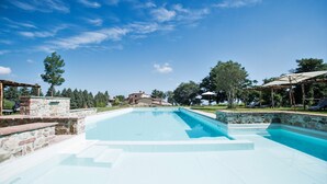 Ein Schwimmbecken mit Steinstufen und einer Pergola.