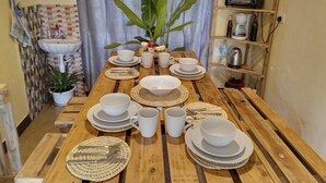 A wooden dining table set with white plates, bowls, and cups, surrounded by woven placemats. - 
🏡 Peaceful Family Retreat in Arusha – Near National Parks & City Center (Arusha)