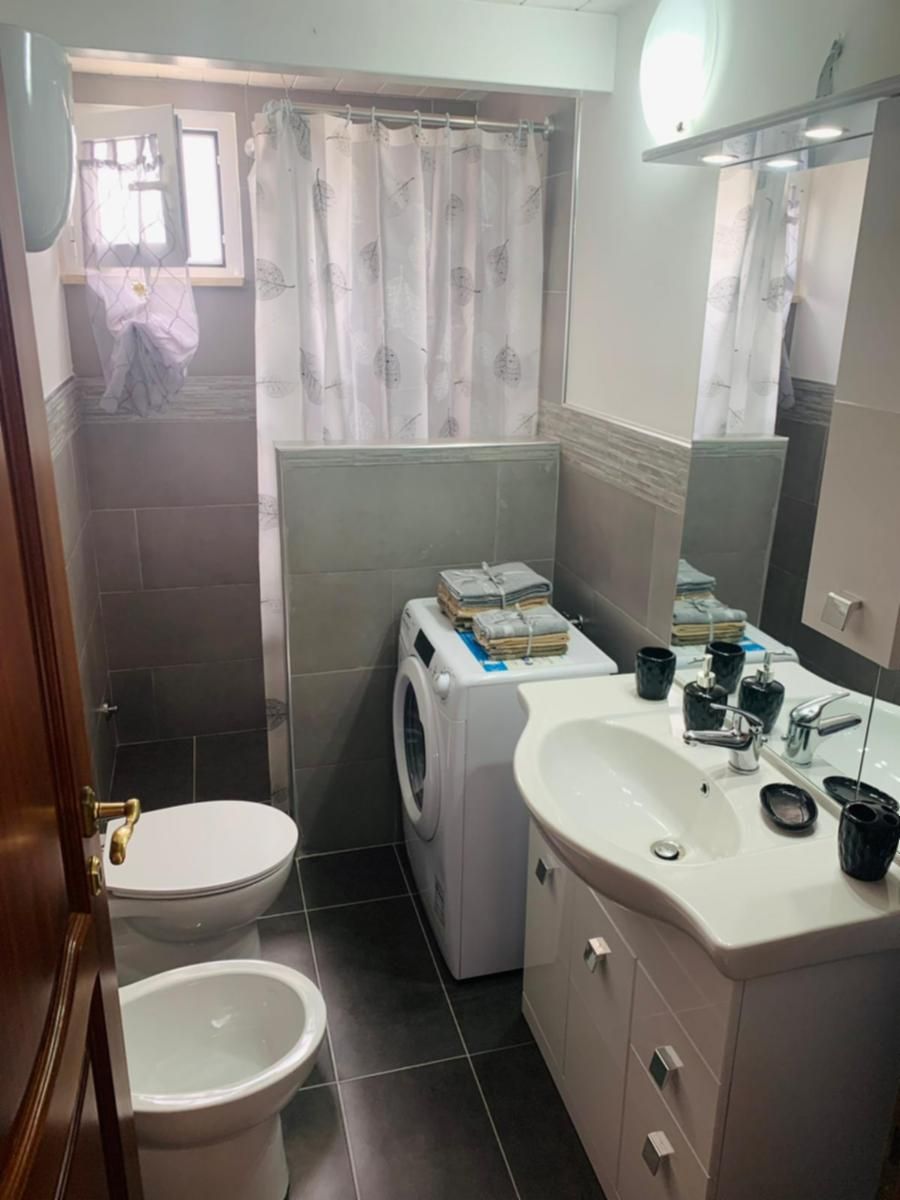 Une petite salle de bain comprenant des toilettes, un lave-linge et un lavabo.
