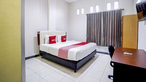 Une chambre d’hôtel avec un lit, un bureau et une fenêtre avec des rideaux.