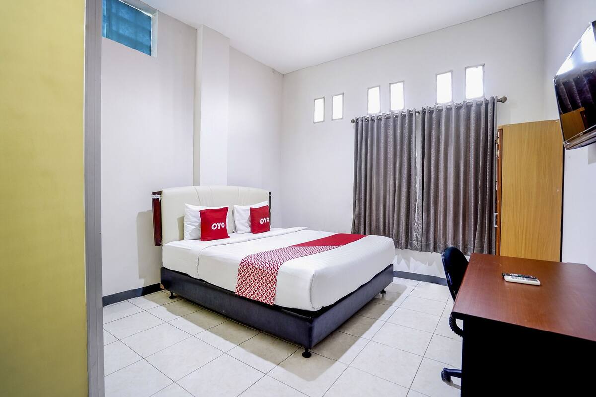 Una habitación de hotel con una cama, un escritorio y una ventana con cortinas.