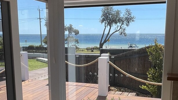 Une pièce dotée d’une grande porte-fenêtre coulissante qui donne sur une terrasse offrant une vue sur la mer.