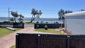 Une propriété résidentielle offrant une vue sur l’océan, une allée pavée et un patio couvert.