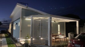 Une maison moderne dotée d’un patio entièrement vitré, d’une voiture garée devant et d’un petit jardin.