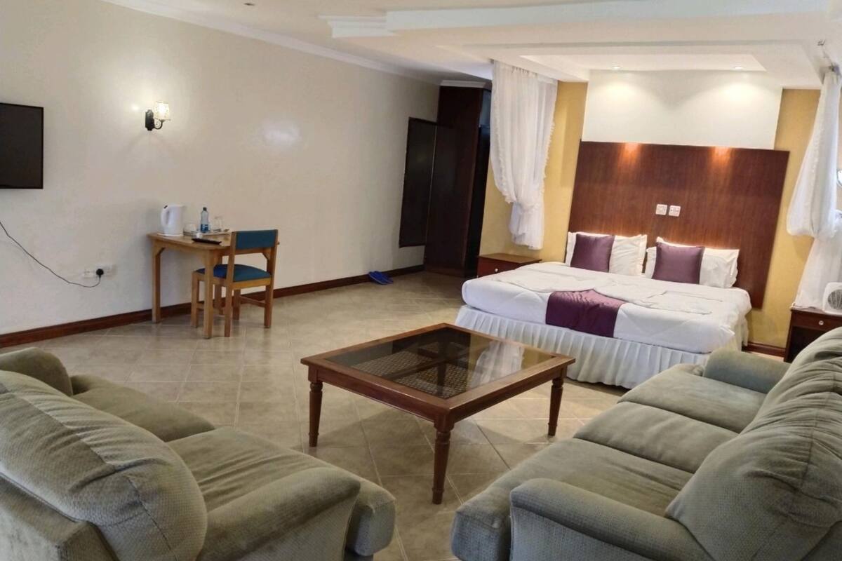 A hotel room with a bed, two sofas, a small table, a desk, and a chair.
