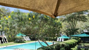 Uma área de piscina com escorrega, guarda-sóis e assentos.