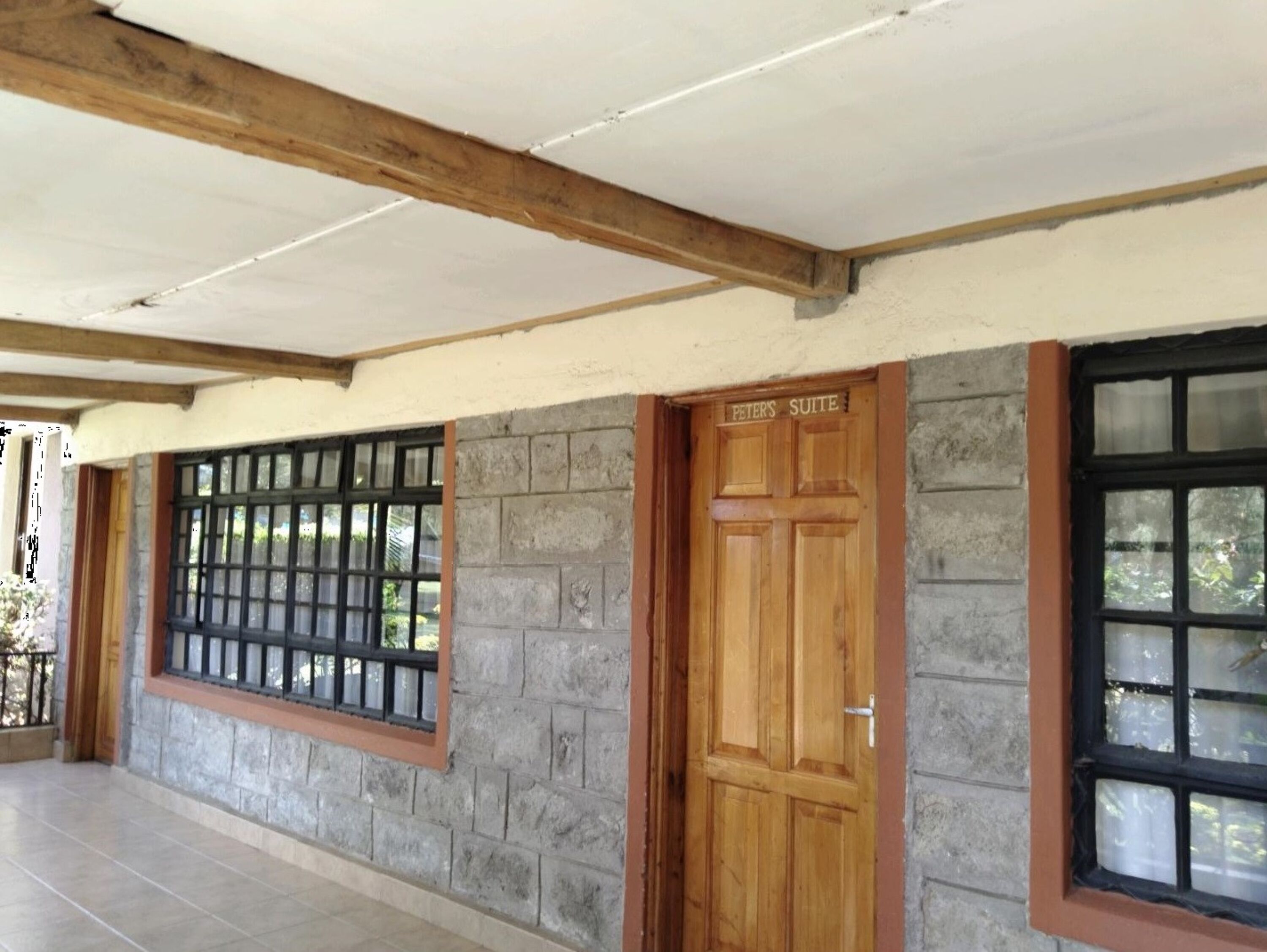 Un edificio con facciata in pietra, una porta in legno con la scritta "Peters Suite" e una finestra dotata di sbarre metalliche.