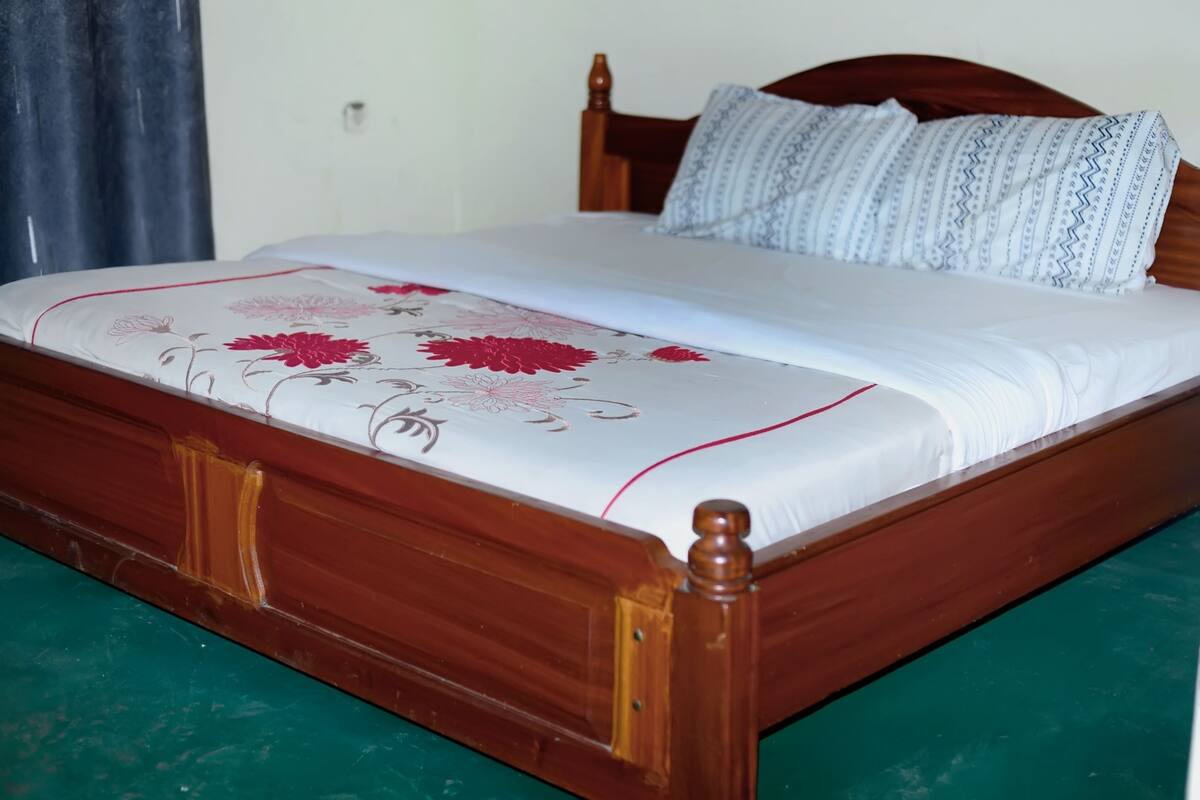 A wooden bed with a floral bedspread and patterned pillows.