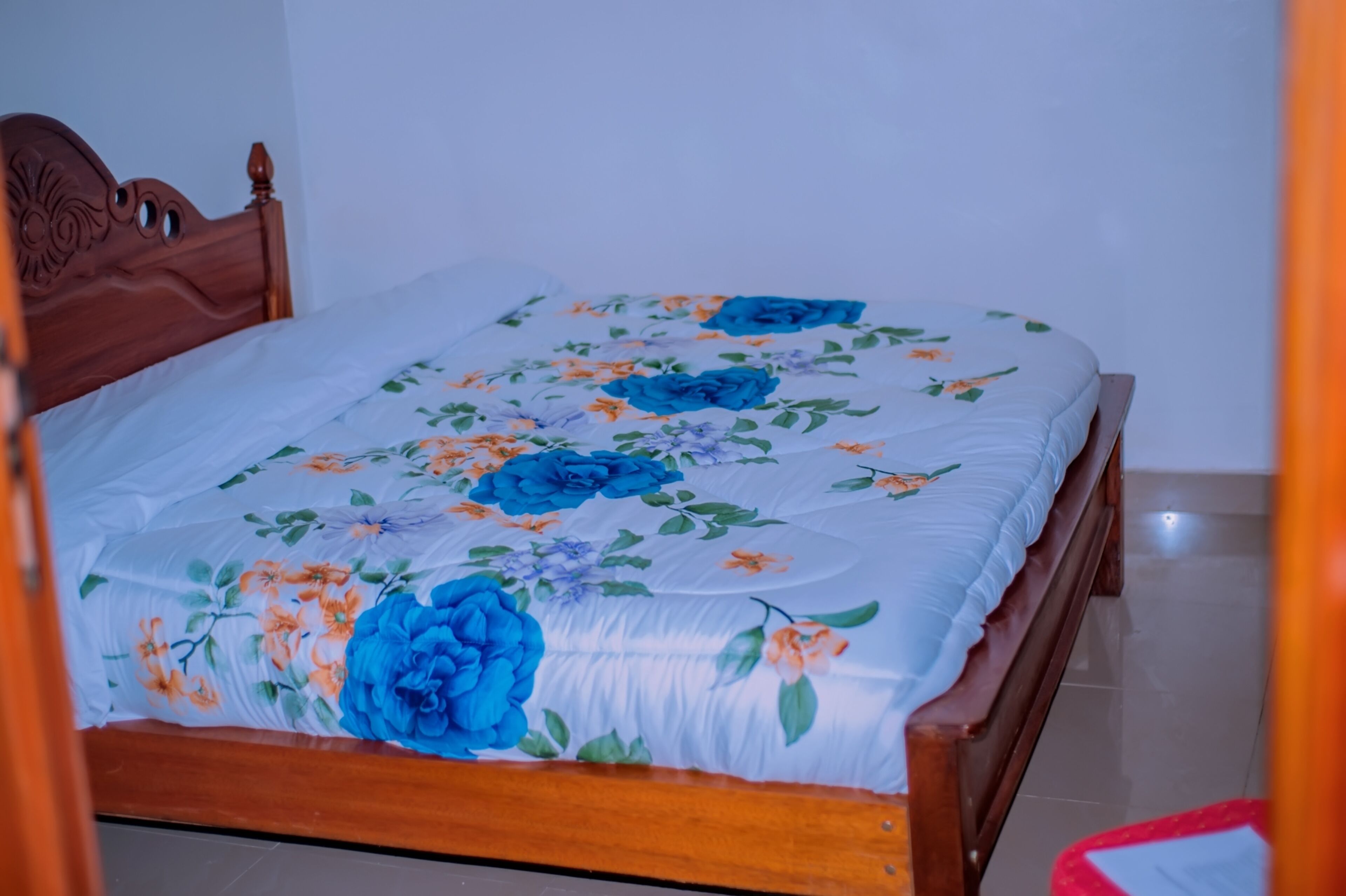 A neatly made bed with a floral bedspread and a wooden headboard.
