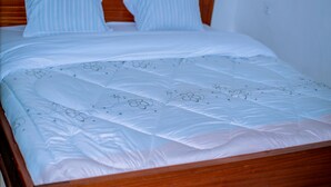 Una cama bien hecha con un edredón estampado con motivos florales y dos almohadas a rayas.