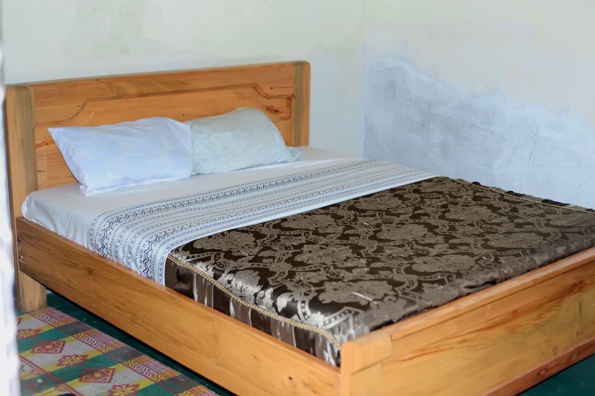 A wooden bed with a patterned bedspread and pillows.