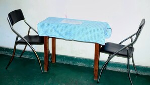 Una mesa con mantel azul, dos sillas negras y base de madera.