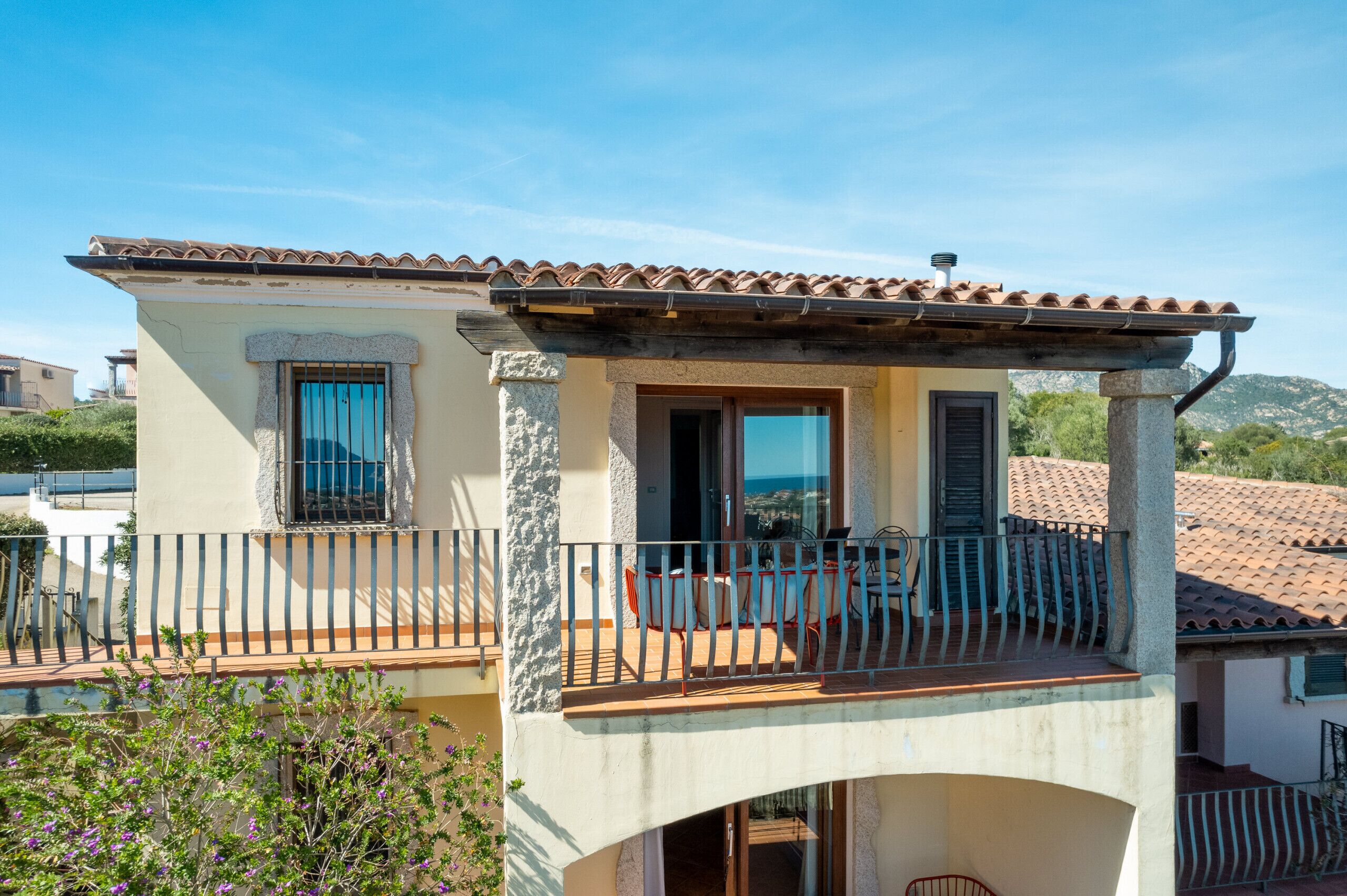 A two-story building with a balcony, a pool, and a mountain view.