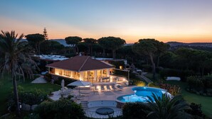 Uma villa luxuosa com piscina, área de estar externa e um jardim bem cuidado.