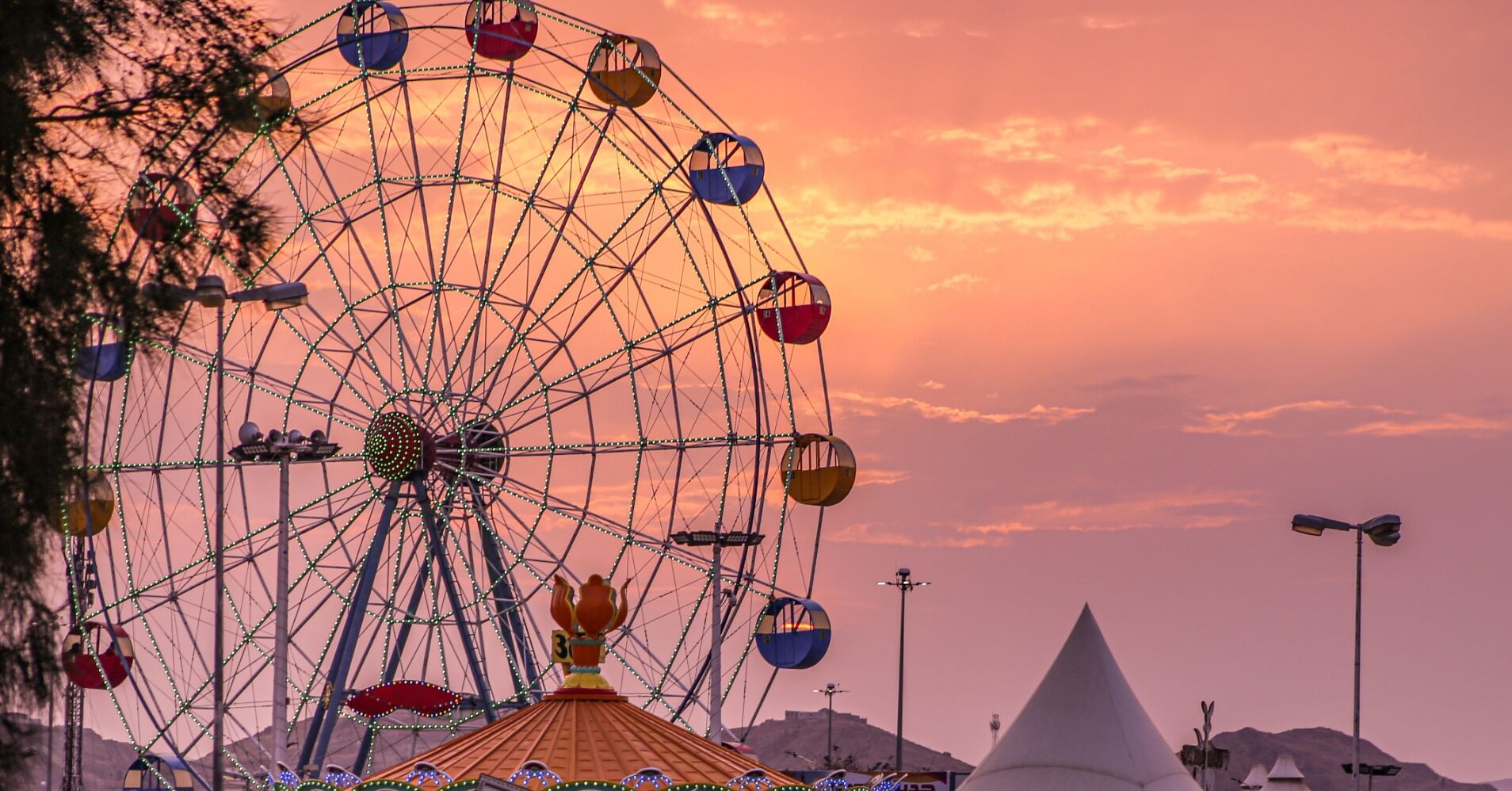 A large Ferris wheel with gondolas at a fairground.