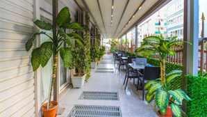 A covered outdoor seating area with potted plants and tables. - Antalya Residence Hotel (Antalya)