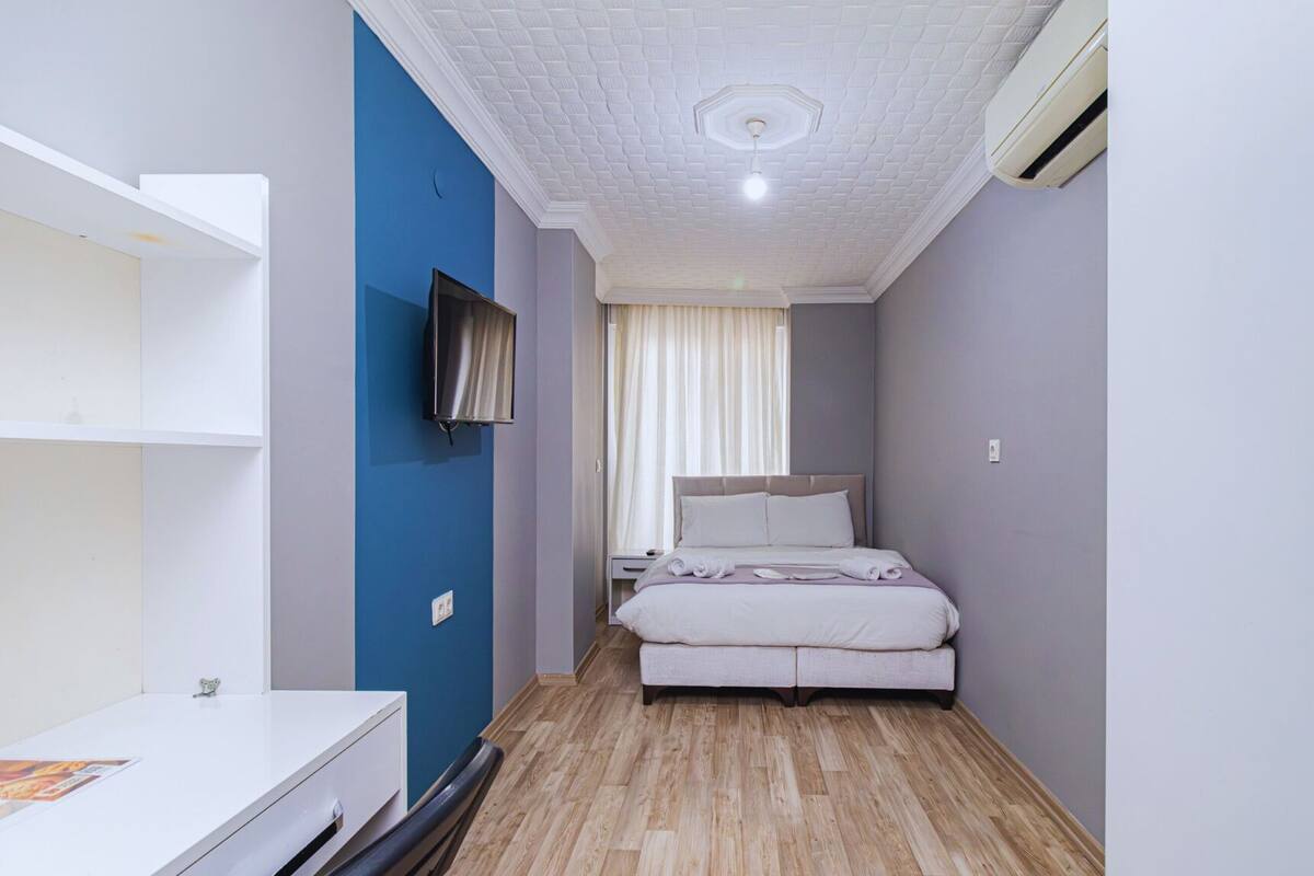 A compact hotel room with a bed, a TV, a desk, and a wardrobe.