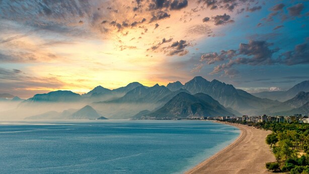 Un paysage côtier comprenant des montagnes, une plage et une vue sur la ville.