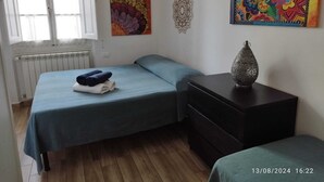 Une chambre avec deux lits, une commode et un radiateur.