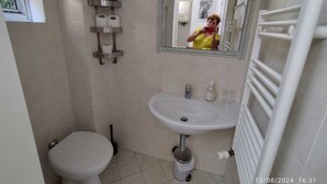 Une salle de bain avec des toilettes, un lavabo et un miroir.